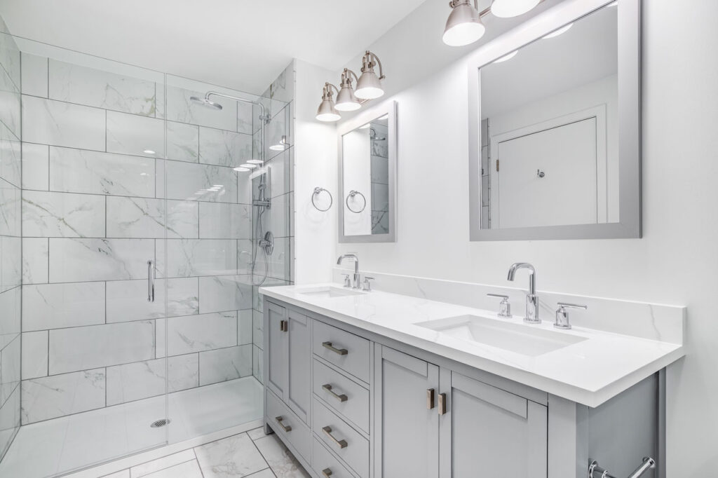 Elegant bathroom with gray marble tiles in the shower area, complemented by a double vanity and modern lighting fixtures.