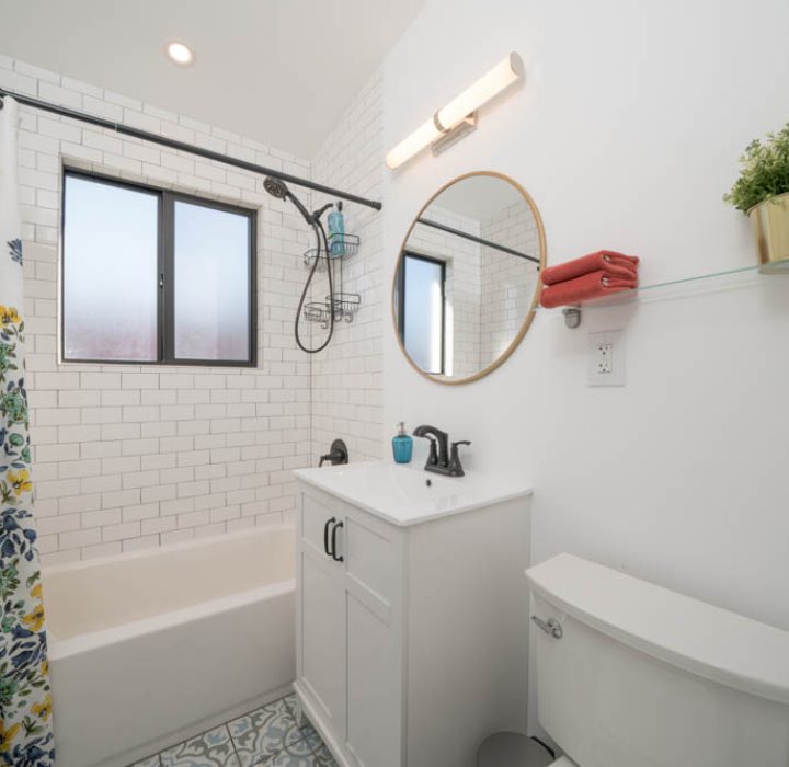 A small, inviting bathroom with a floral shower curtain, subway tiles, and a contemporary sink vanity, providing a fresh and clean look.