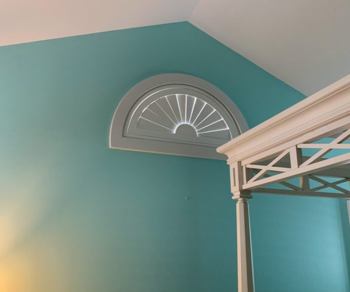 A custom-designed bathroom featuring a unique fanlight window over a bed, painted in soothing turquoise to enhance the room's decor, demonstrating specialized interior renovation skills.